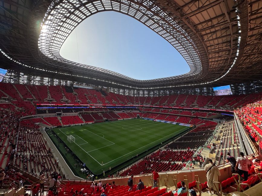 A stunning view of a modern stadium with a soccer field and partially filled seats.