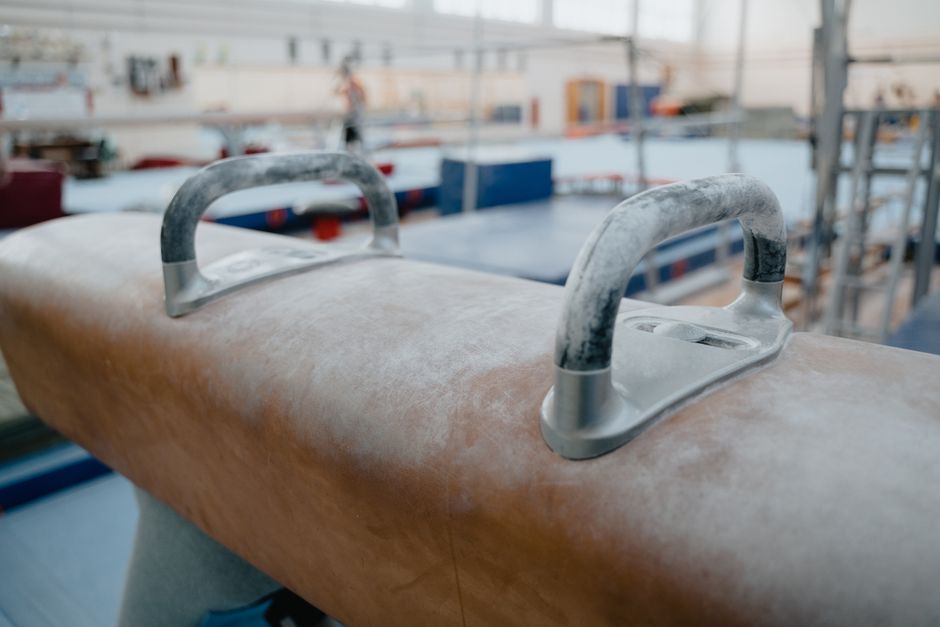Detailed view of a pommel horse in an indoor gym with blurred background.